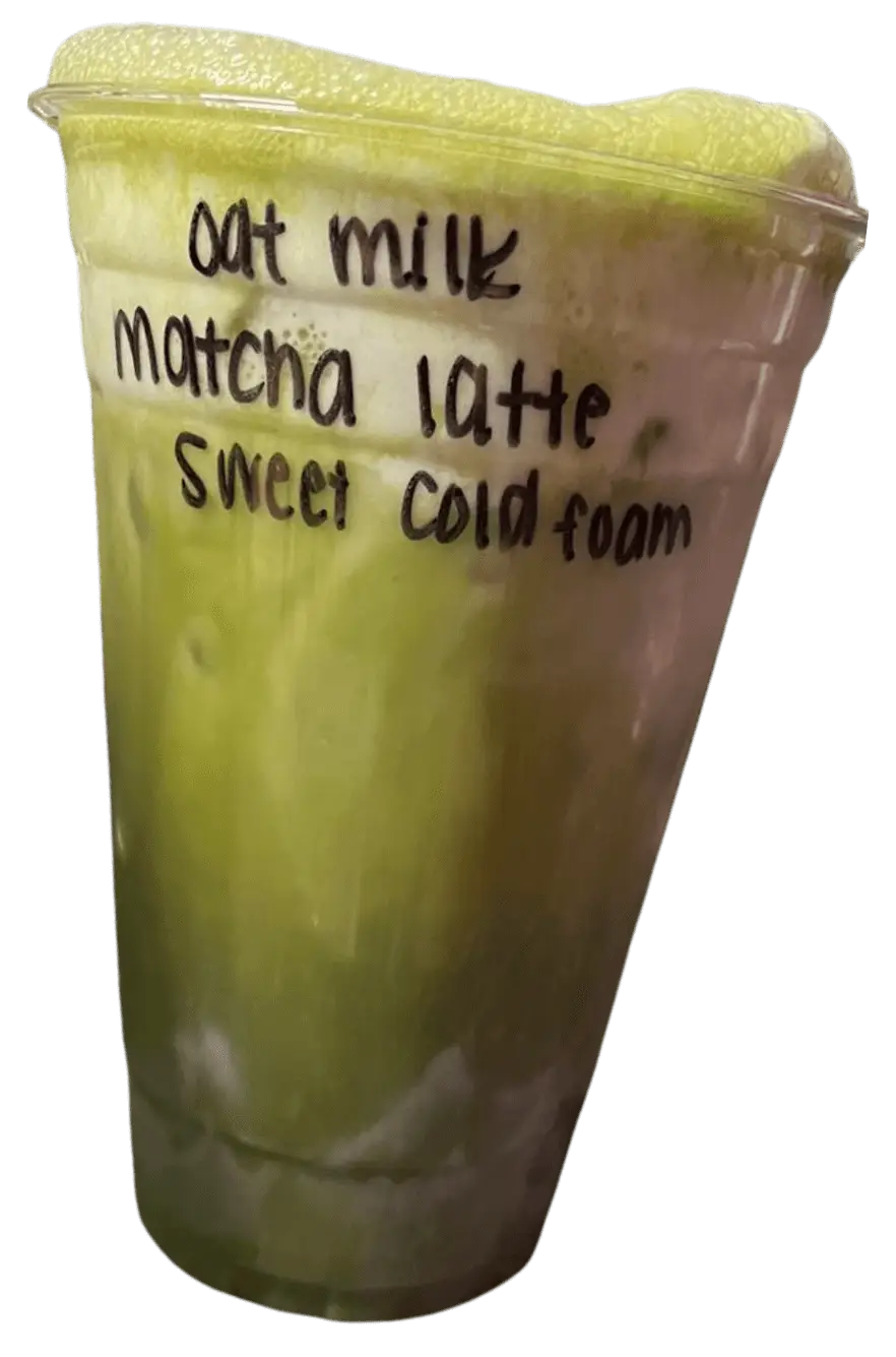 A clear cup filled with a layered oat milk matcha latte topped with sweet cold foam, labeled with its ingredients.